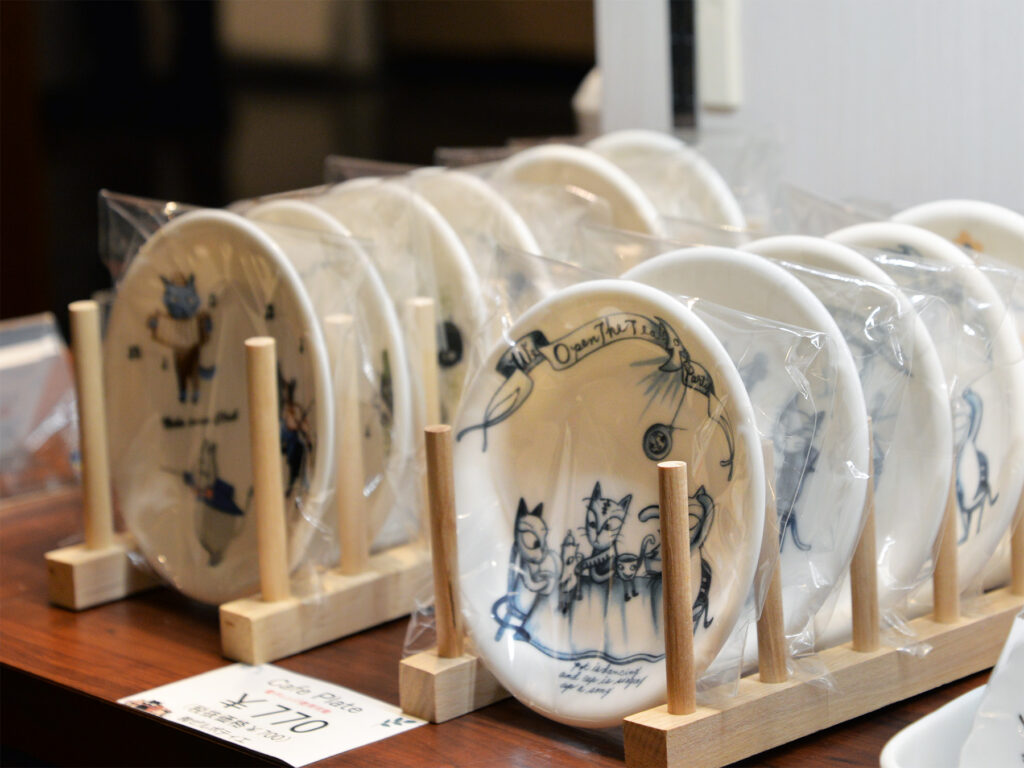 シンジカトウさんデザインの猫のイラストが陶器のお皿に描かれたゼルポティエオリジナル商品の画像です。