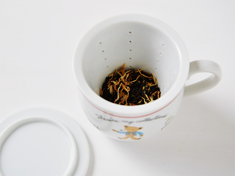 美濃焼の白いハーブマグカップにおしゃれな可愛さのくまのイラストが描かれているハーブマグカップにハーブティの茶葉を入れた様子の画像です。