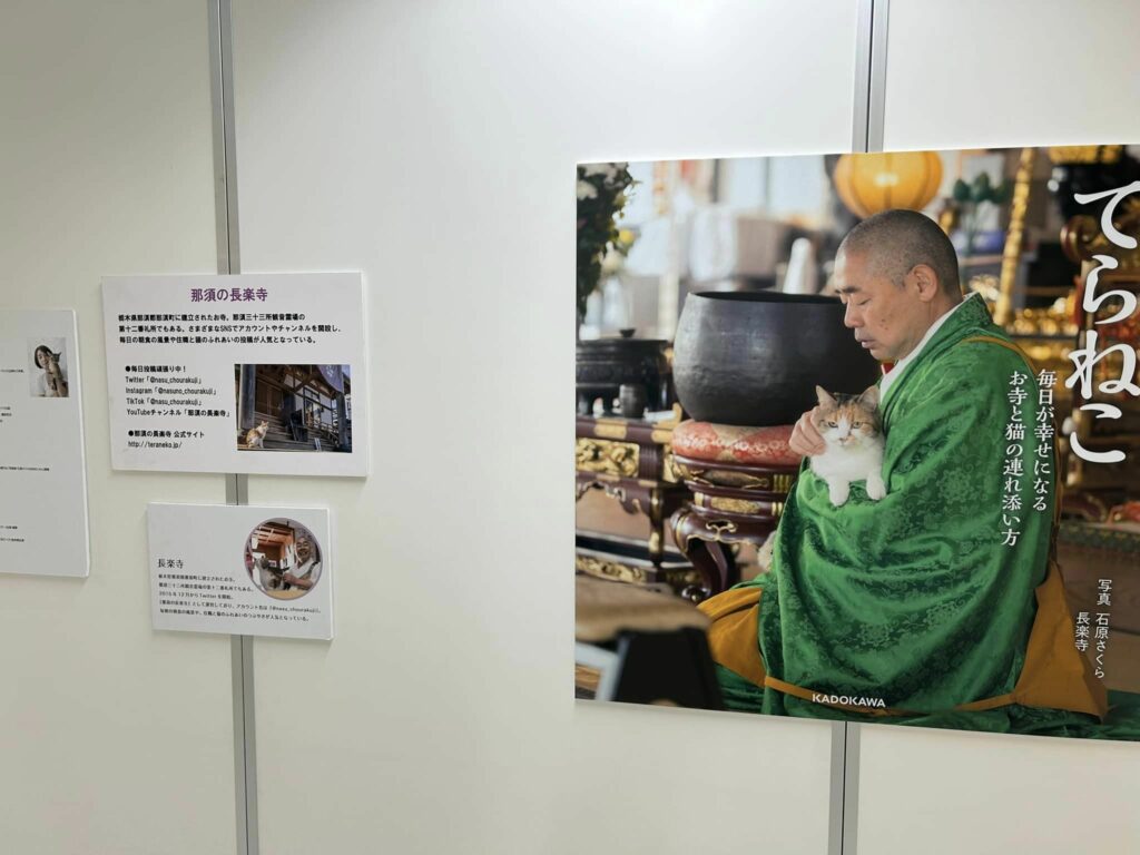 写真家石原さくらさんが、ねこてら長楽寺の住職が優しく猫を抱いている写真のパネル写真