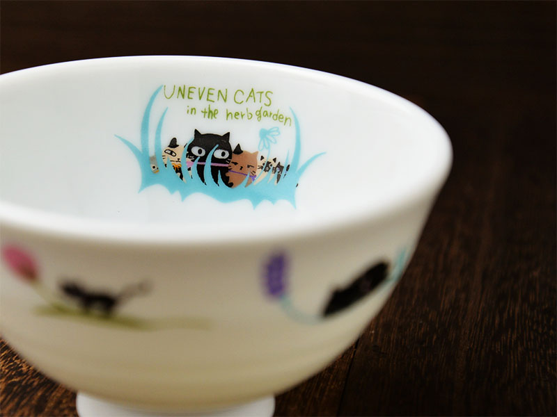 美濃焼の白い陶磁器の生地にデザイナーシンジカトウさんが猫のイラストを描いたお茶碗の内側にも可愛い6匹の猫のイラストが描かれたアニーブンキャッツシリーズのお茶碗の画像です。