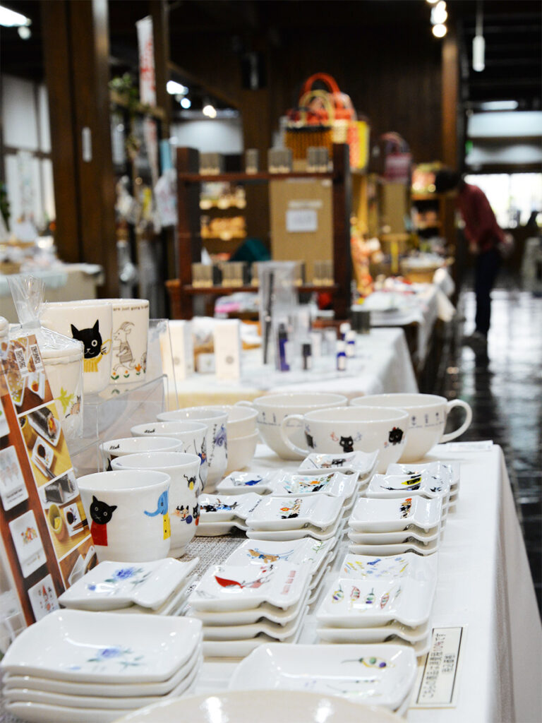 ゼルポティエの白い陶磁器製の箸置き小皿に猫や赤ずきんちゃんなどが描かれた商品の販売している様子の画像です。