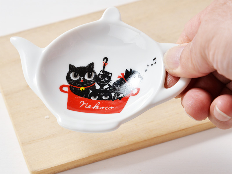 直径10cm位の大きさのティーポットの形を小皿にしたティートレーです。
小皿の中央に5匹の猫が赤い鍋にぎゅうっと詰まって入り込んでいる様子が描かれている商品画像です。