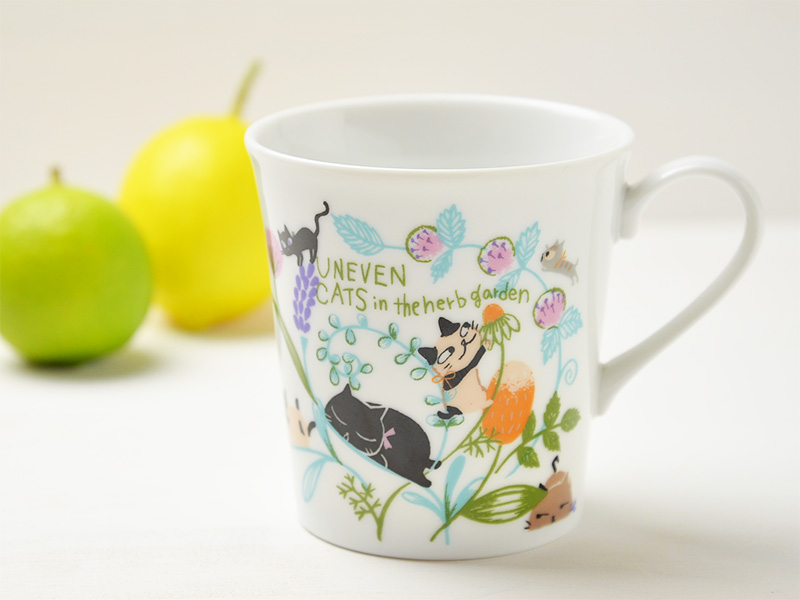 雑貨デザイナーシンジカトウさんデザインの可愛い猫のイラストのシリーズ「アニーブンキャッツシリーズ」の白さに拘った白磁の生地に猫達が草原の中でくつろぐ様子が描かれたマグカップです。