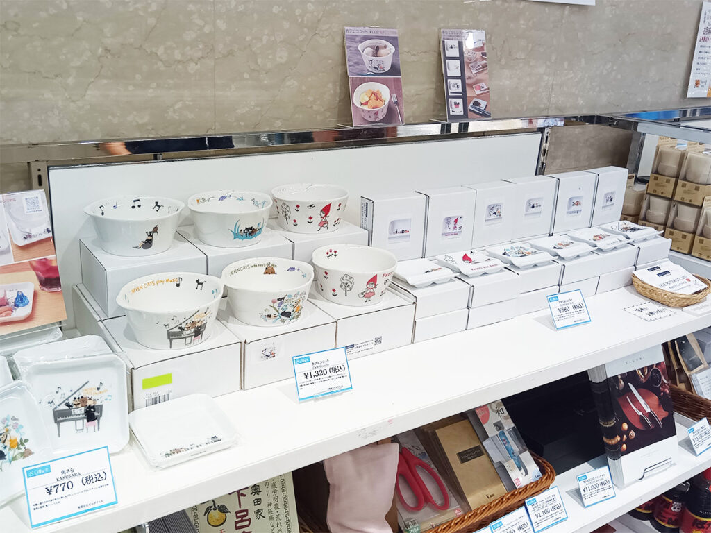 大阪駅前ダイヤモンド地下街の「ディーズスクエア ディアモール大阪、ディーズスクエアで開催の清流の国ぎふ博覧会で雑貨デザイナーシンジカトウ　Shinzi katohさんデザインのゼルポティエの可愛い猫のイラストや赤ずきんちゃんのイラストの美濃焼製の陶器、食器の販売の様子の画像です。