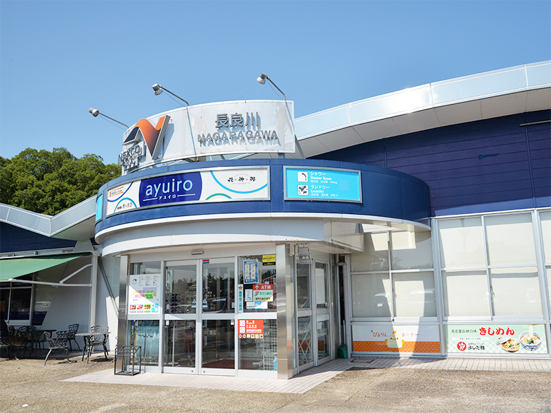 東海北陸自動車道 長良川サービスエリアの正面入り口。青い空の下、白い建物と「長良川 NAGARAGAWA」の大きな看板が写っています。