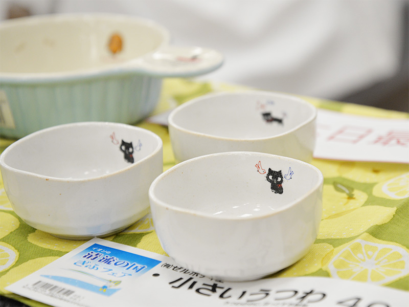 白い小さな鉢（小鉢）が3つ並んでおり、それぞれに黒猫のイラストがシンプルに描かれている。背景はレモン柄の布。