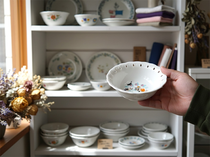 食器棚の前で、アニーブンキャッツのフリルボウルを手に持つ様子。コレクションしたくなる「北欧風 食器 白」のイメージ。
