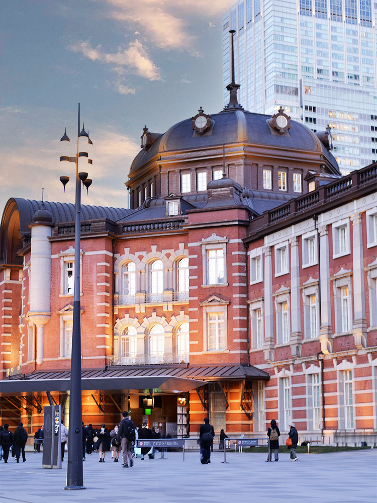 夕暮れ時の美しい東京駅・丸の内駅舎。歴史ある赤レンガの建物と都会的な高層ビルが並ぶ景色は、仕事帰りにふらりと「丸猫展」へ立ち寄りたくなる、洗練された大人の街並みです。