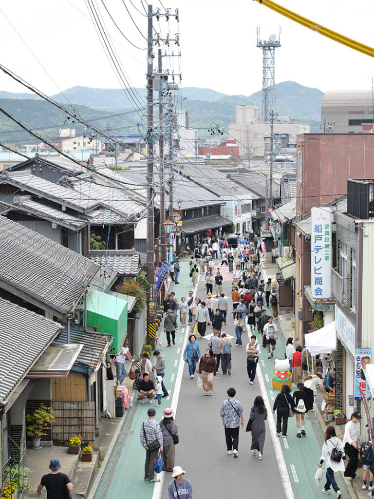 たじみ陶器まつりのメイン通りを俯瞰した写真。青空の下、多くの来場者で賑わうストリートと白いテントが並ぶ活気ある風景。