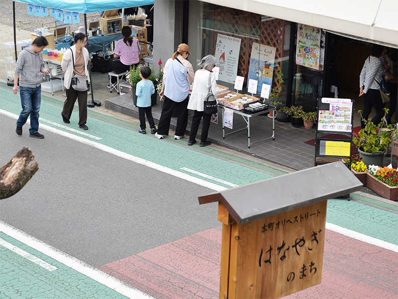 呉服店の店先にディスプレイされたゼルポティエの器。通りを歩く人々が足を止めてシンジカトウデザインの陶磁器を眺めている様子。