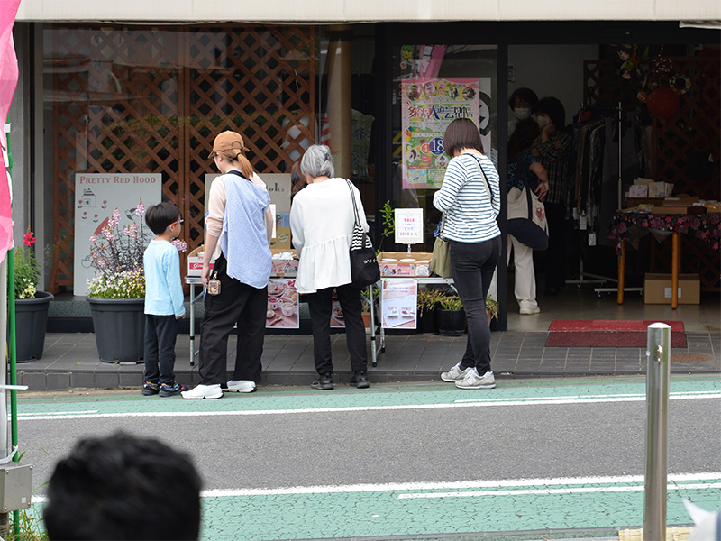 【たじみ陶器まつり】呉服屋店内の木製テーブルに美しく並べられたシンジカトウデザインの美濃焼。白地に繊細なラインで描かれた小鳥や植物、幾何学模様の平皿やボウルが、奥の鏡に映り込みながら奥行きを感じさせるようにディスプレイされている。使い勝手の良さそうなサイズ感と、手作りの温かみが伝わる店頭風景。