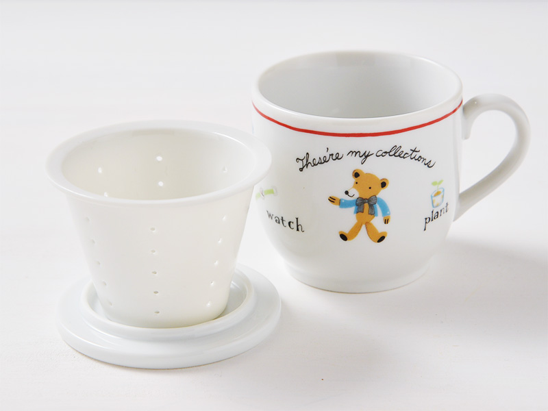 ハーブマグカップから磁器製ストレーナー(茶漉し)を取り出し、裏返したマグカップの蓋の上にトレイとして載せて、マグカップの横に並べて置いている様子。