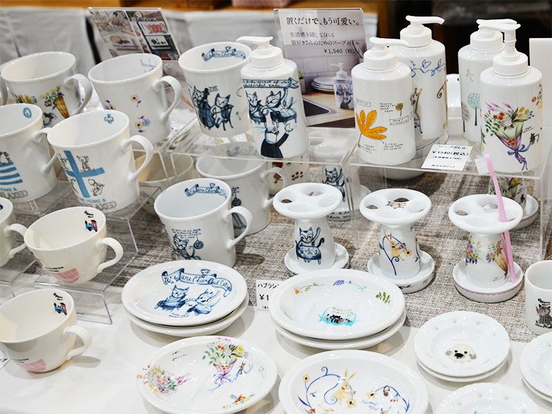 10月2日に「香恋の館」へ商品補充を行った際のテーブル展示。Designed by Shinzi Katoh(シンジカトウ)の可愛い猫や草花が描かれたソープボトル、歯ブラシスタンド、マグカップ、小皿などが隙間なく整然とディスプレイされています。