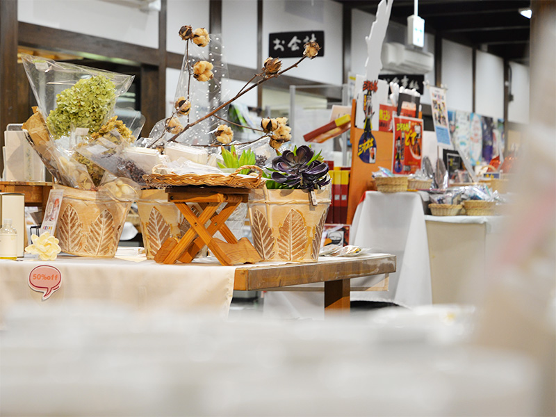 10月2日に「香恋の館」店内へ商品補充に伺った際の売り場の様子。温かみのある木のテーブルに、葉っぱの模様が彫られた陶器の鉢カバーやドライフラワー、コットンフラワーの枝などが華やかにディスプレイされています。